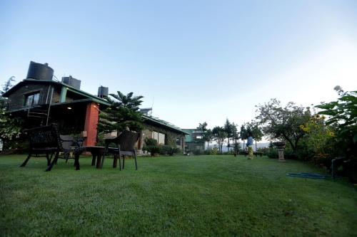 a yard with chairs and a table in front of a house at Cedar Lodge By Aahma in Rāmgarh