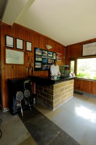 a man is sitting at a counter in a room at Cedar Lodge By Aahma in Rāmgarh
