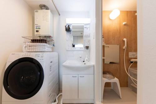 uma casa de banho com uma máquina de lavar roupa e um lavatório em SERENADE em Chitose