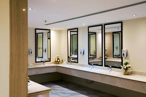 Baño con 4 lavabos y una fila de espejos en Helat Hotel, en Al Khobar