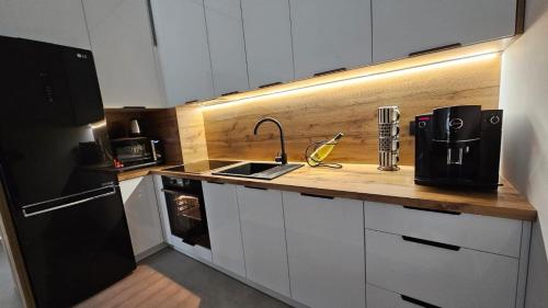 a kitchen with a sink and a black refrigerator at Kolo Apartament Gold in Koło