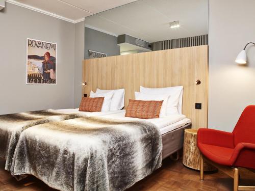 une chambre d'hôtel avec un lit et un fauteuil rouge dans l'établissement Original Sokos Hotel Vaakuna Rovaniemi, à Rovaniemi