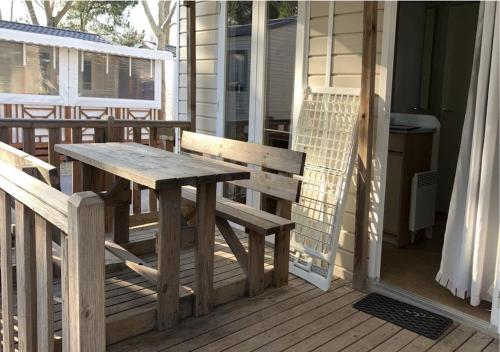 un tavolo in legno e una panca sul portico di una casa di Mobil-home Camping - La Marine - Grau du Roi a Le Grau-du-Roi