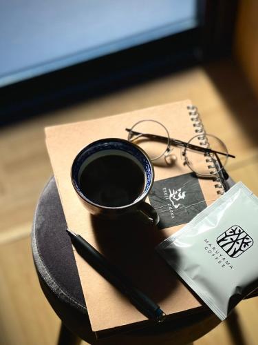 a cup of coffee and a pen on a table at サウナ付き一棟貸し宿 大岡辻-tsuji oooka- in Ookanakamaki