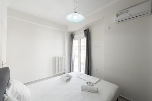 a white room with a bed with two towels on it at New Spacious & Stylist Apt in Piraeus