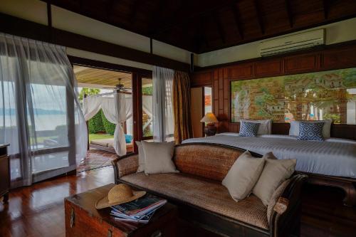 a bedroom with a large bed and a couch at Miskawaan Beachfront Villas in Mae Nam