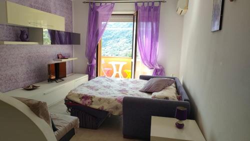 1 dormitorio con 1 cama y una ventana con cortinas moradas en Isola del Giglio casa Nico e casa Camilla Monticello Giglio Porto, en Isola del Giglio