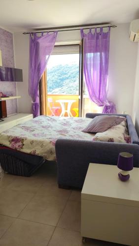 a bedroom with a bed with purple curtains and a window at Isola del Giglio casa Nico e casa Camilla Monticello Giglio Porto in Isola del Giglio