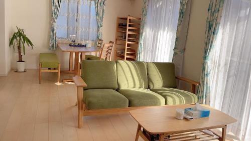 a living room with a green couch and a table at 有間宿泊 in Tokoname