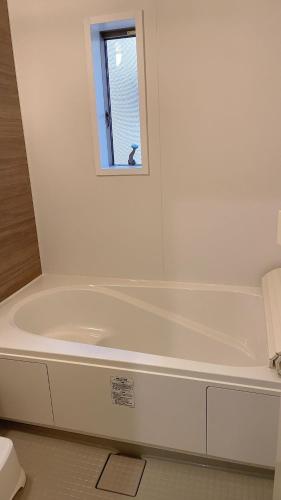 a white bath tub in a bathroom with a window at 有間宿泊 in Tokoname