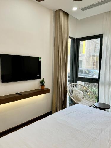 a bedroom with a tv and a bed and a chair at Tropicana Hồ Tràm - Seashell Villa in Ho Tram