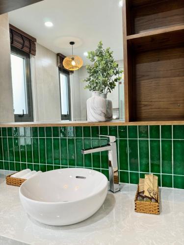 a bathroom with a white sink and a green tiled wall at Tropicana Hồ Tràm - Seashell Villa in Ho Tram