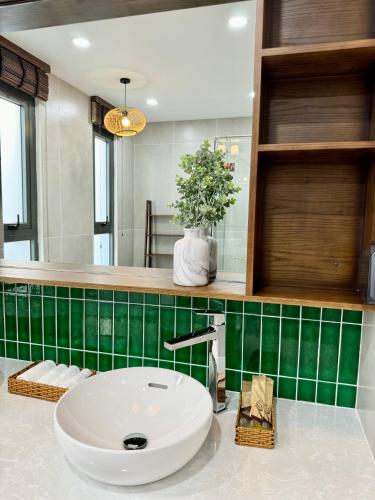 a bathroom with a sink and a green tiled wall at Tropicana Hồ Tràm - Seashell Villa in Ho Tram