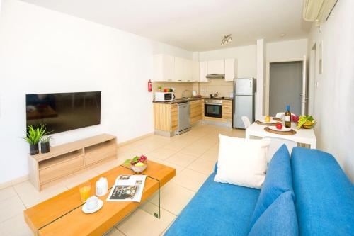 a living room with a blue couch and a kitchen at LULA - Beachfront Apartment in Paralimni