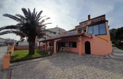 a house with a palm tree in front of it at Apartmani Delas 2 in Pješčana Uvala 