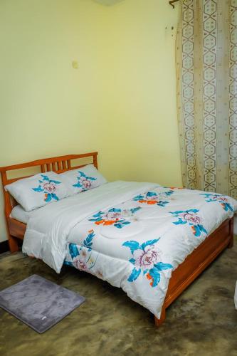 a bed with a white blanket with flowers on it at Rhoja homes in Ruhengeri