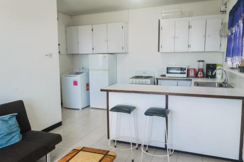 a kitchen with a counter and two stools at Oceans Rental Apartments in DʼArbeau