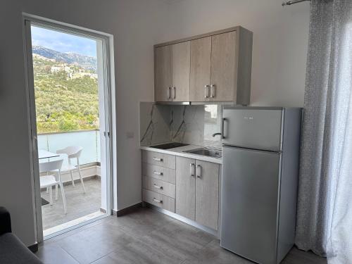 a kitchen with a refrigerator and a table and a window at Vila Melina in Himare