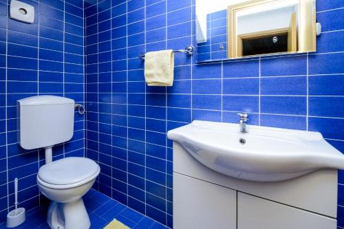a blue tiled bathroom with a toilet and a sink at Celtis Apartment in Mlini