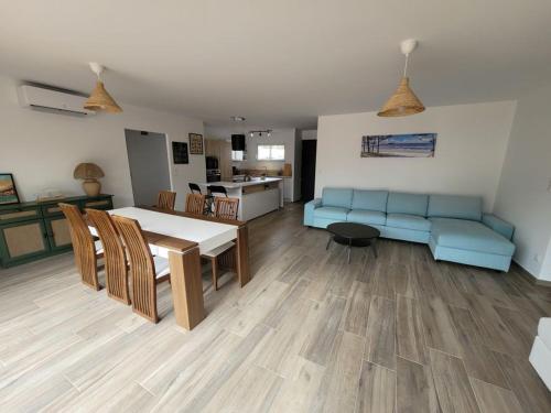 un salon avec une table et un canapé bleu dans l'établissement MAISON 4 CHAMBRES PISCINE CHENAL DES DUNES, à Saint-Jean-de-Monts