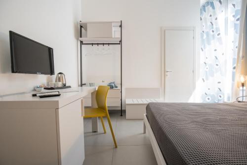 a bedroom with a bed and a desk with a television at BMode in Catania