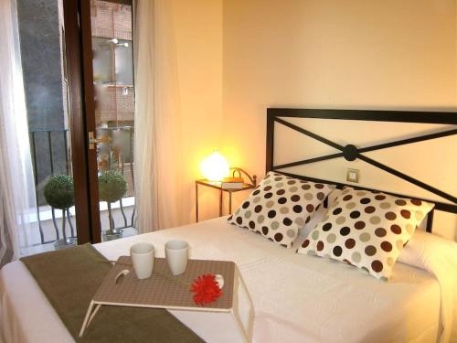Una cama con una bandeja con dos tazas. en Balcón con luz natural, en Madrid