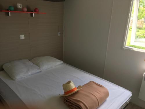 Camping Campilo - Maeva في Aubigny: سرير فيه قبعة جالس عليه