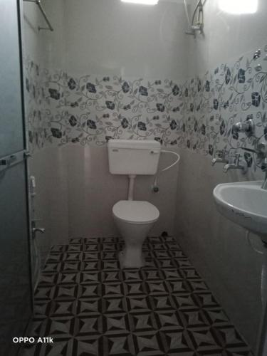 Baño en blanco y negro con aseo y lavamanos en Shruti Guest House, en Dublāt