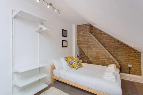 a bedroom with a white bed and a brick wall at Сharming & Peaceful 3BDR flat near Wembley station in London