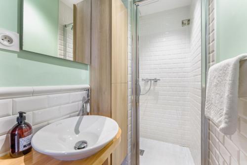 une salle de bain avec un lavabo blanc et une douche dans l'établissement Le Petit Bacchus - au cœur de Nantes, à Nantes