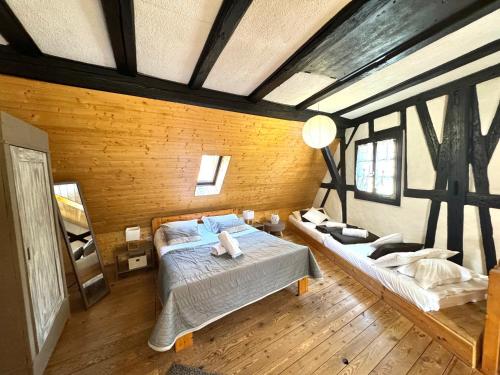 a bedroom with two beds and a wooden wall at Gîte "L'Escale du Vignoble" à Ribeauville in Ribeauvillé