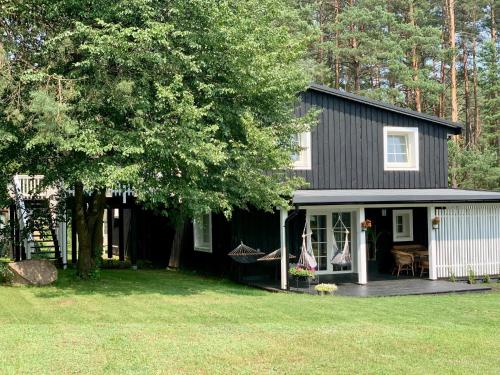 ein schwarzes Haus mit einer Veranda und einem Hof in der Unterkunft Pušyno apartamentai in Druskininkai