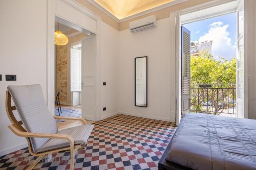a bedroom with a bed and a chair and a balcony at Real Tenuta Apartments By Domus Sicily in Palermo