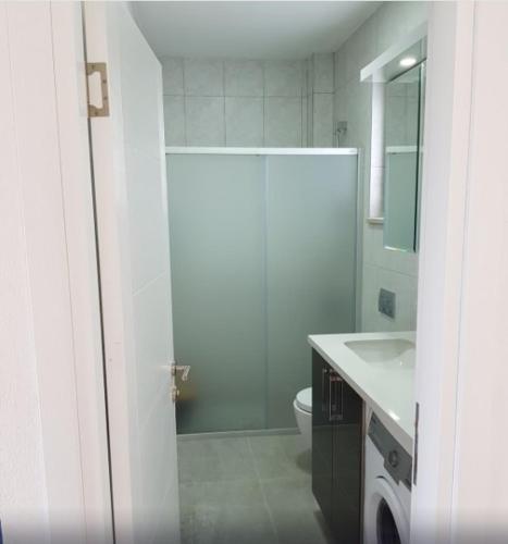 a white bathroom with a toilet and a sink at Datça Zeytinevleri Apart in Datca