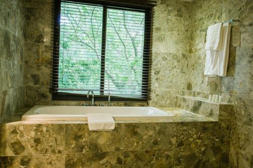 a bathroom with a bath tub with a window at FLAMIGO Đại Lải - Villa Tự Doanh in Phúc Yên