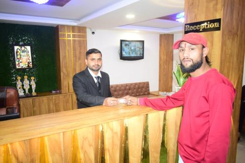 two men are shaking hands over a wooden counter at Hotel Signor in Indore