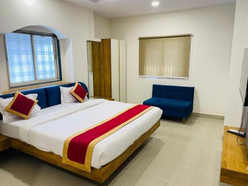 a bedroom with a large bed and a blue chair at Hotel Signor in Indore