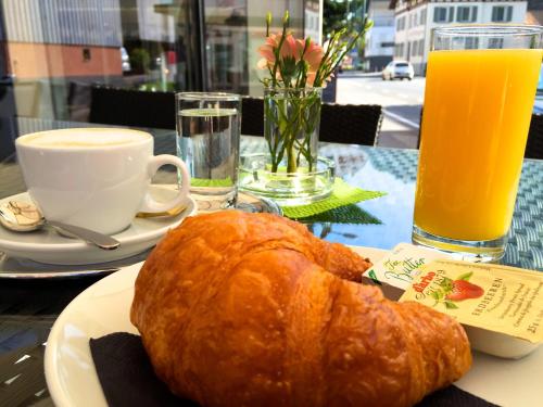 einen Teller mit einem Laib Brot auf einem Tisch mit Orangensaft in der Unterkunft Hotel Café Schatz in Hohenems