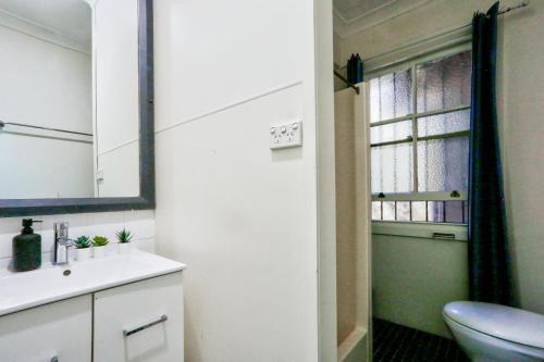 łazienka z umywalką, toaletą i oknem w obiekcie Affordable 3 Bedroom House Darlinghurst with 2 E-Bikes Included w mieście Sydney