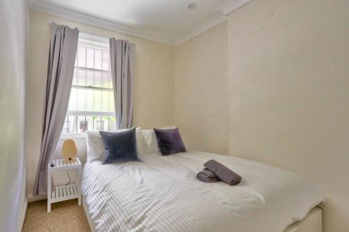 una camera da letto con un letto bianco con cuscini blu e una finestra di Affordable 3 Bedroom House Darlinghurst with 2 E-Bikes Included a Sydney