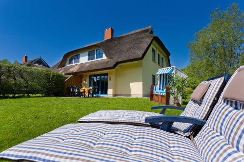 a couple of chairs sitting on a lawn in front of a house at Reetdachhaus Eibe 2, Kaminofen, Sauna, 8 Personen, W-Lan in Puddemin