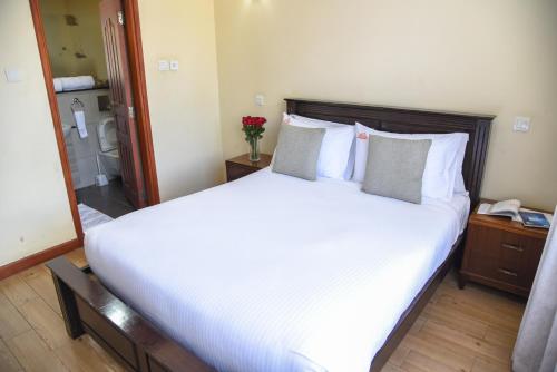 a bedroom with a large bed with white sheets and pillows at Fedha Residences by Trianum in Nairobi