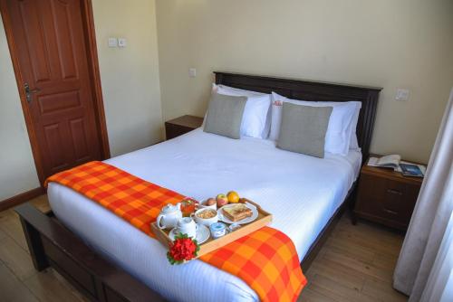 a hotel room with a bed with a tray of food at Fedha Residences by Trianum in Nairobi