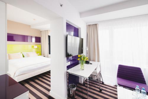 a hotel room with a bed and a table with flowers at Hola Hotel Katowice in Katowice