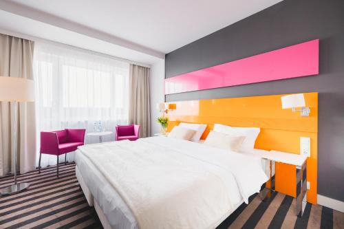 um quarto de hotel com uma grande cama branca e detalhes rosa em Hola Hotel Katowice em Katowice