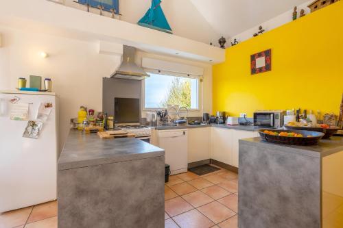 a kitchen with yellow walls and a white refrigerator at Belle grande maison vue mer in Tréogat