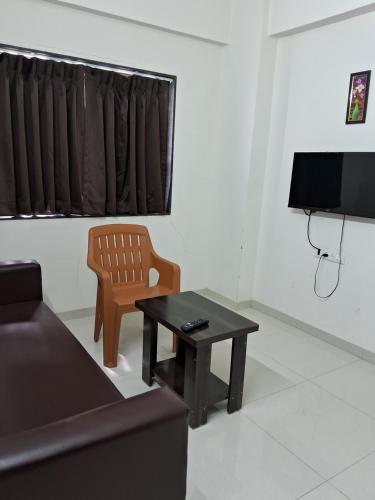 a living room with a couch and a table and a television at Paradise inn in Alandi