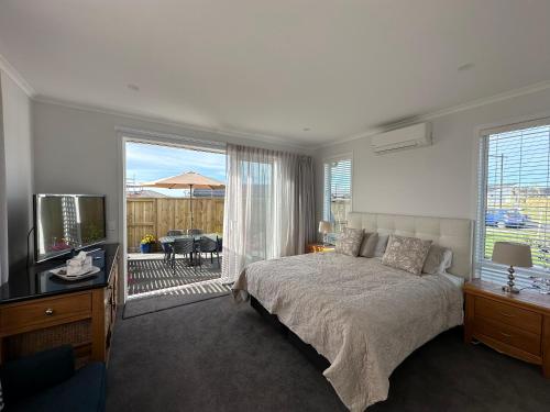 a bedroom with a bed and a television and a balcony at Studio on Patete in Taupo