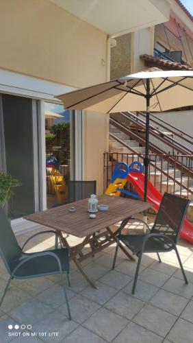 a wooden table and chairs with an umbrella on a patio at Diacopto Country Houses in Diakopto