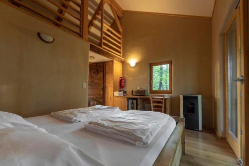 a bedroom with a bed with white sheets on it at Na Skaluc - Country estate & Glamping in Trobni Dol